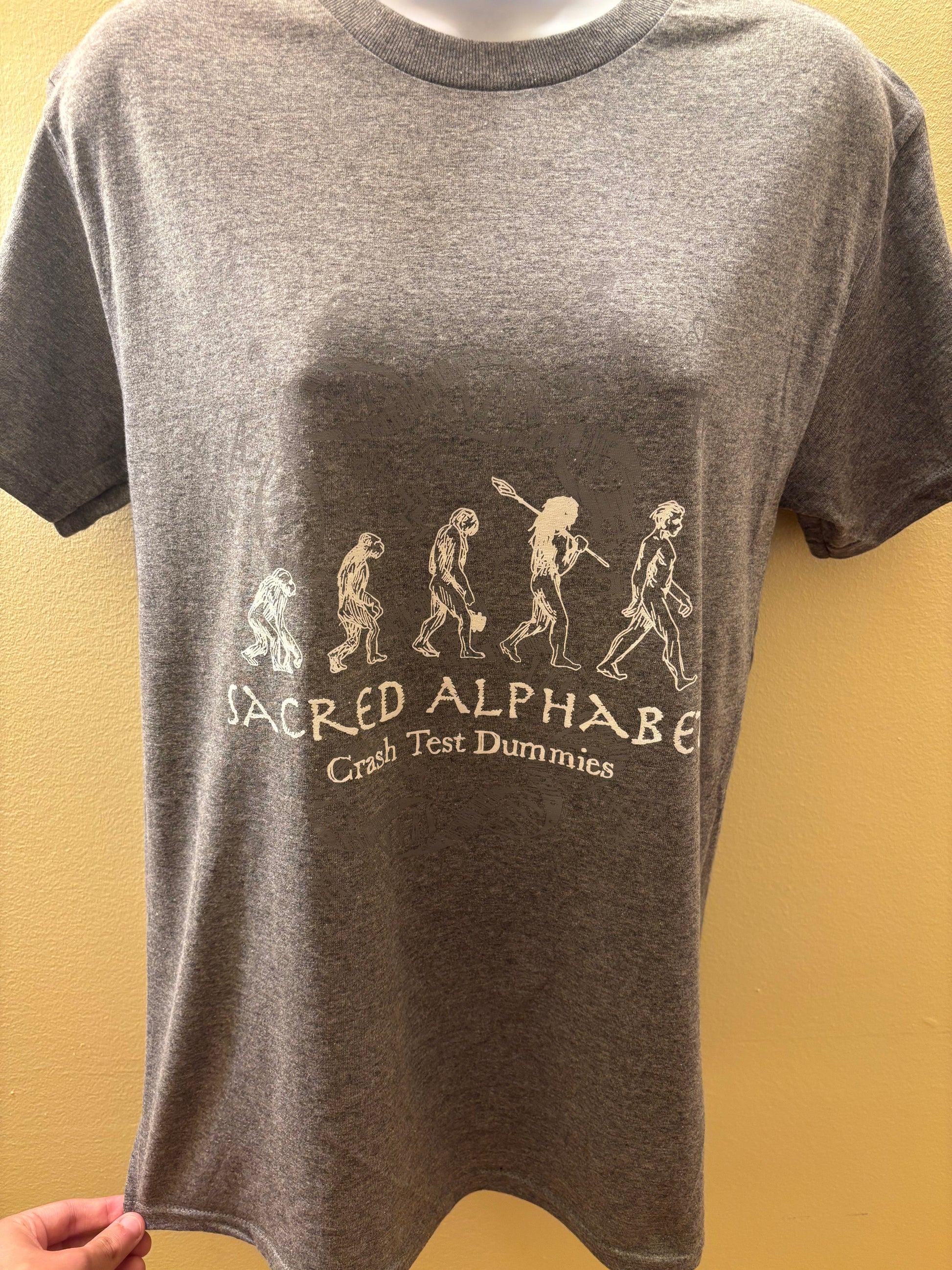 Gray t-shirt with 'Sacred Alphabet' text and design on a yellow background
